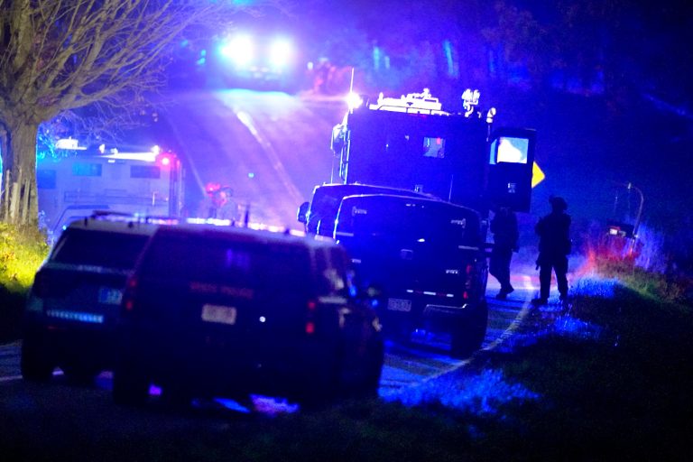 Law enforcement officers, right, stand near armored and tactical vehicles, center, near a property on Meadow Road, in Bowdoin, Maine, Thursday, Oct. 26, 2023. Hundreds of police and FBI agents continued searching for Robert Card, an Army reservist authorities say fatally shot a number of people at a bowling alley and a bar Wednesday.