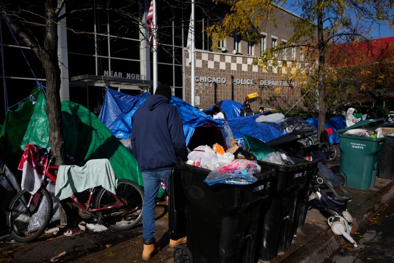 A man walks through a small tent community, Wednesday, Nov. 1, 2023, near a Northside police station in Chicago.