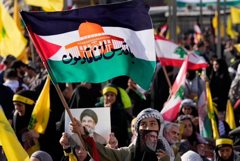 A supporter of the Iranian-backed Hezbollah group waves a Palestinian flag with Arabic words that read: 