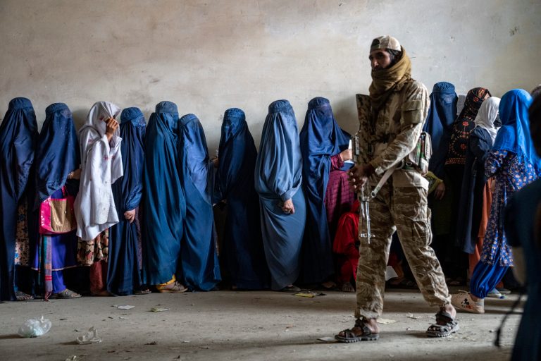 FILE - A Taliban fighter stands guard as women wait to receive food rations distributed by a humanitarian aid group on May 23, 2023, in Kabul, Afghanistan.