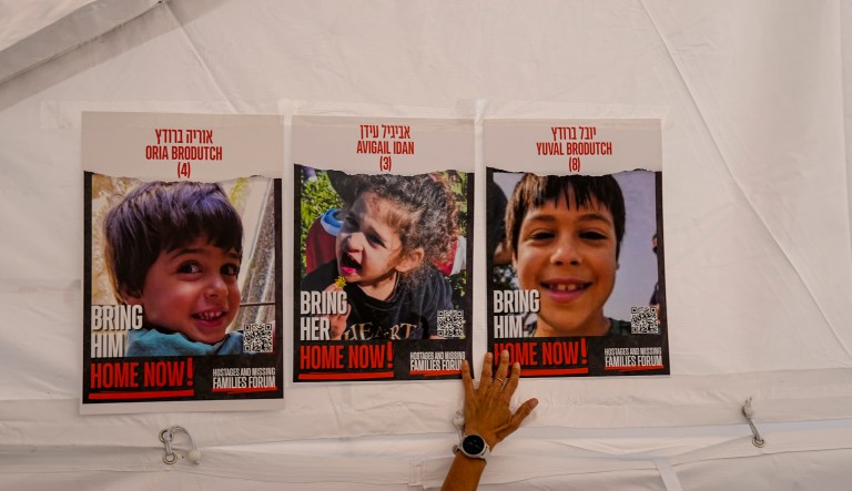 A woman plasters photos of Israeli children from Kibbutz Kfar Azza missing and held captive in Gaza on Tuesday, Nov. 21, 2023, in Tel Aviv, Israel. The hostages, mostly Israeli citizens, were kidnapped during an Oct. 7 Hamas cross-border attack in Israel and have been held in Gaza since then.