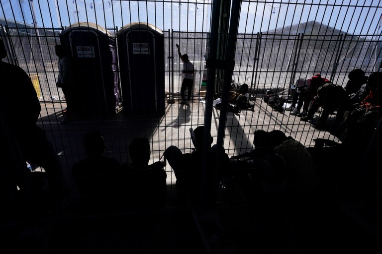 Men wait in a holding area Friday, Dec. 15, 2023, at a Border Patrol station in Ajo, Arizona.