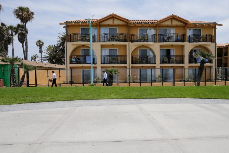 In this June 10, 2016 picture, hotel owner Elvin Lai, left, takes an inspection walk with an intern around the exterior of his hotel in San Diego. (AP Photo/Gregory Bull)