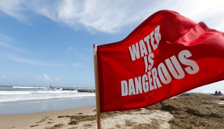 A warning flag flies from a lifeguard's vehicle as he patrols the beach during a break in the rain and wind storms in Virginia Beach, Va.
