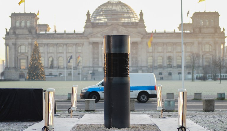 An oversized urn covered with a black plastic wrap placed by the artist group 'Center for Political Beauty" in front of German parliament building, the Reichstag in Berlin, Germany, Thursday, Dec. 5, 2019. An activist group has apologized to Jewish groups who expressed outrage at an urn placed in front of the German parliament that the activists claim contains Holocaust victims' remains. The Center for Political Beauty said late Wednesday they had not intended to hurt the feelings of Holocaust survivors and their descendants when they placed the urn in front of Reichstag building Monday.