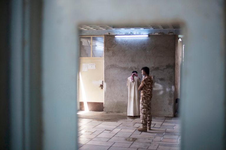 A blindfolded Islamic State suspect stands against a wall at a Kurdish screening center in Dibis on Oct. 3. Displaced people from Hawija are brought to the center where men are separated from the women and children and are investigated for involvement in the Islamic State group. (AP Photo/Bram Janssen)
