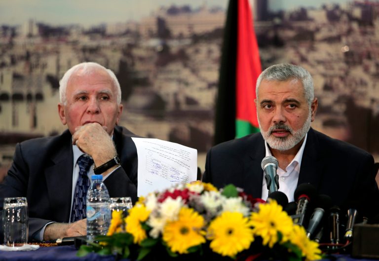Gaza's Hamas Prime Minister Ismail Haniyeh, right, shows a copy of a singed agreement while siting next to senior Fatah official Azzam al-Ahmad during their press conference after the announcement of an agreement between the two rival Palestinian groups, Hamas and Fatah, at Haniyeh's residence in Shati Refugee Camp, Gaza Strip, Wednesday, April 23, 2014. Hamas and Fatah made a new attempt Wednesday to overcome the Palestinians' political split, saying they would seek to form an interim unity government within five weeks, followed by general elections by December at the earliest.  It was not clear how the new attempt announced Wednesday would succeed where previous ones failed, since the fundamental difficulties remain in place. (AP Photo/Adel Hana)