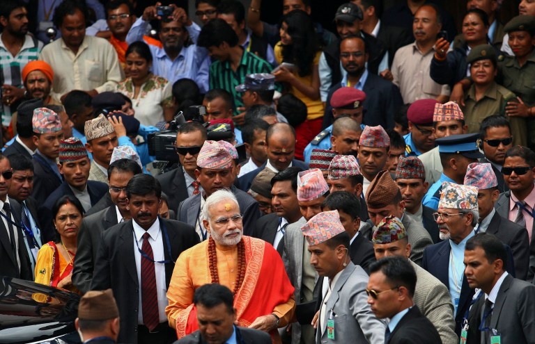 Indian Prime Minister Narendra Modi, foreground in saffron clothing, leaves after his visit at the Pashupatinath Temple in Katmandu, Nepal, Monday, Aug. 4, 2014. Modi flew to the neighboring Himalayan nation Sunday to meet top leaders, offer prayers at a revered Hindu temple and address the parliament. (AP Photo/Kiran Panday)