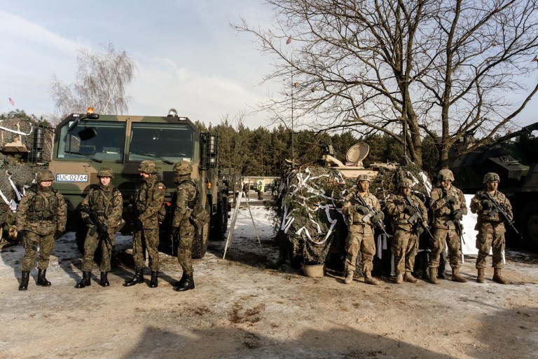 U.S. Army soldiers, right, and Polish Army soldiers stand in front of their vehicles as they wait for the opening of their joint exercise in Poland. (AP Photo/Krzysztof Zatycki)