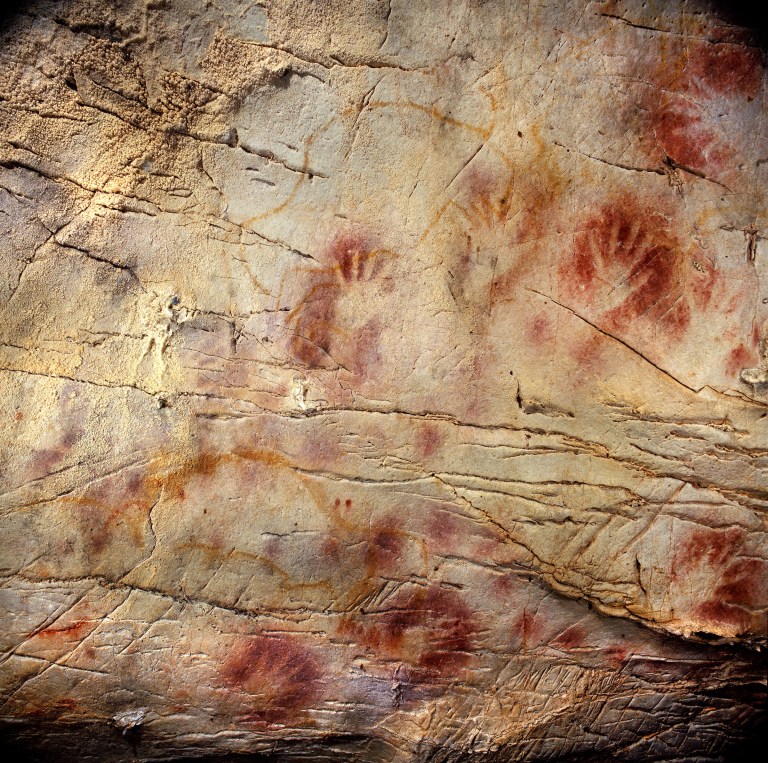   This undated handout photo provided by pedro suara/aaas shows detail of the 'Panel of Hands', El Castillo Cave showing red disks and hand stencils made by blowing or spitting paint onto the wall. A date from a disk shows the painting to be older than 40,800 years making it the oldest known cave art in Europe. The bison overlay the hands and are therefore painted later. New tests show that crude Spanish cave paintings of a red sphere and handprints are the oldest in the world, so ancient they may not have been by modern man. They might have even been made by the much-maligned Neanderthals, some scientists suggest but others disagree. (AP Photo/Pedro Saura, AAAS)  