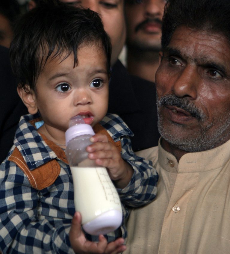 An unidentified family member with a nine-month-old boy, leave after the boy's court appearance in Lahore, Pakistan, Saturday, April 12, 2014. A Pakistani lawyer said a judge has freed the boy accused of attempting to murder police in the eastern city of Lahore after police withdrew charges. (AP Photo/K.M. Chaudary)