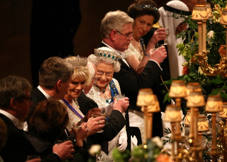 Britain's Queen Elizabeth II toasts with President of Ireland Michael D. Higgins, obscured 5th left, after her speech during a State Banquet in honour of the Irish President, in Windsor Castle Tuesday April 8, 2014, in Windsor, England.  Guests and dignitaries including Irish Prime Minister, Enda Kenny and Northern Ireland's Deputy First Minister Martin McGuinness are attending the banquet at the end of the first day of a state visit by Ireland's Michael D. Higgins. Higgins is making the first state visit by a president of the republic since it gained independence from Britain. Camilla Duchess of Cornwall at 4th left, and Princess Anne, 2nd right. (AP Photo / Dan Kitwood)