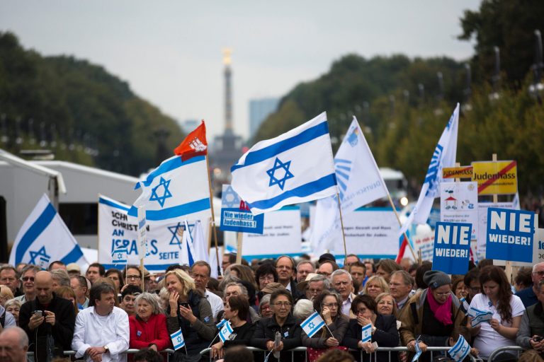 People with Israeli flags and banners, reading 'never again,'attend a rally against anti-Semitism in Berlin. (AP Photo/Markus Schreiber, Pool)