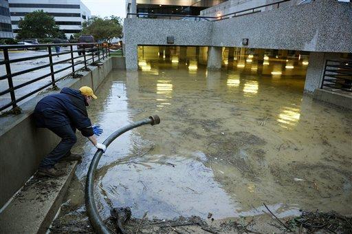A worker places the intake tube for a water pump into nearly four-feet of water early Friday, Sept. 9, 2011, that had flooded a parking garage in Alexandria, Va. on Thursday evening. (AP Photo/Cliff Owen)