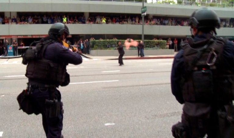 In this July 6, 2013 still frame from a video produced by the Los Angeles Police Department, officers fire on a woman posing as a terrorist in a drill simulating a terrorist attack in downtown Los Angeles. After spending a decade sending military equipment to civilian police departments across the United States, Washington is reconsidering the idea in light of the violence in Ferguson, Mo., amid images of heavily-armed police, snipers trained on protesters and tear gas plumes. One night after the violence that accompanied the presence of military-style equipment in Ferguson, the crowd calmed considerably when a police captain walked through the crowd, unprotected, in a gesture of reconciliation. The contrast added to the perception that the tanks and tear gas had done more harm than good. (AP Photo/Los Angeles Police Department)