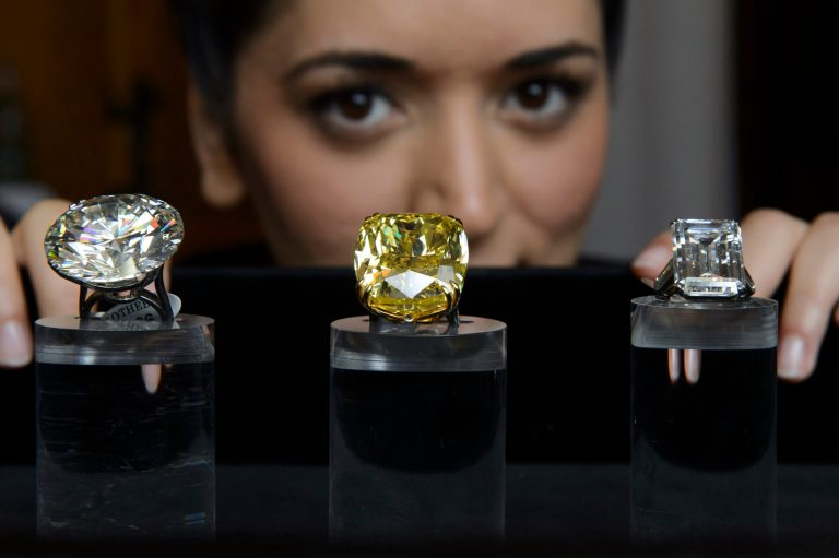 FILE - The May 7, 2014 file photo shows a Sotheby's employee showing three exceptional diamonds during a preview at the Sotheby's, in Geneva, Switzerland. Left to right: one of the world's largest known round brilliant-cut diamonds weighing 103.46 carats, which is estimated to sell between 3,500,000 to 5,000,000 US Dollar, the Graff Vivid Yellow at 100.09 carats, one of the rarest yellow diamonds of its size, which is estimated to sell between 15,000,000 to 25,000,000 US Dollar and the Victory Diamond, a 31.34 carat diamond named to commemorate the allied victory in World War II, which is estimated to sell between 5,000,000 to 8,000,000 US Dollar at the auction in Geneva on May 13, 2014. (AP Photo/Keystone, Martial Trezzini)