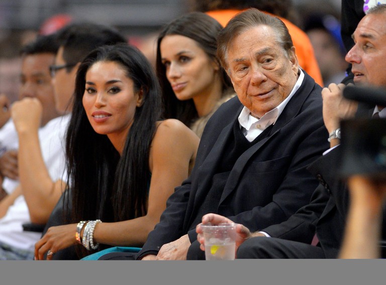 In this file photo taken on Friday, Oct. 25, 2013, Los Angeles Clippers owner Donald Sterling, right, and V. Stiviano, left, watch the Clippers play the Sacramento Kings during the first half of an NBA basketball game in Los Angeles. (AP Photo/Mark J. Terrill, File)