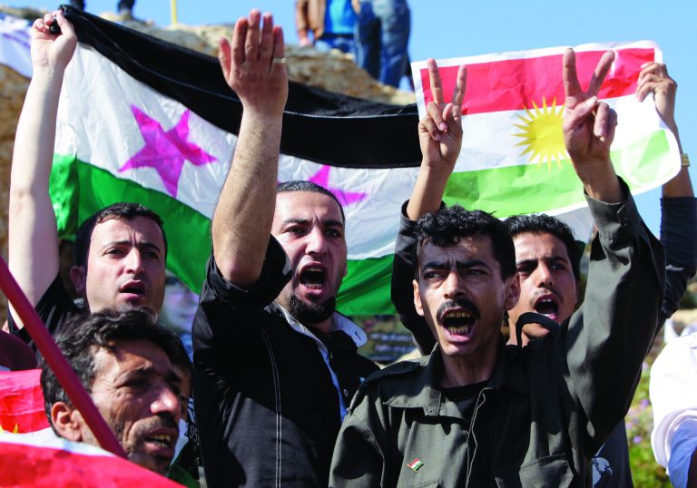 FILE - In this Wednesday, March 21, 2012 file photo, Syrian Kurds living in Lebanon and opposed to Syrian President Bashar Assad, hold up a Kurdish flag, right, and a Syrian revolution flag, left, as they chant slogans against the Syrian regime as they celebrate the Nowruz day in Beirut, Lebanon. Last month, while the world's attention focused on the battles raging in Syria's two largest cities, a quiet transformation was taking place in the country's oil-rich northeastern corner where about 2 million people from Syria's Kurdish minority live. In mid July, shortly after rebels struck in the Syrian capital with unprecedented attacks and a bomb blast that killed four of President Bashar Assad's top security aides, Syrian security forces began pulling back from several towns and villages across the border area, ceding defacto control to armed Kurdish fighters who have since set up checkpoints, hoisted Kurdish flags, and began exercising a degree of autonomy unheard of before. (AP Photo/Bilal Hussein, File)