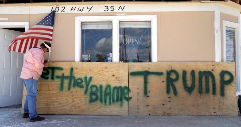 John Murray attaches a U.S. flag to a sign reading 
