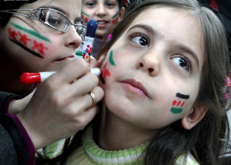 In this citizen journalism image provided by Aleppo Media Center AMC which has been authenticated based on its contents and other AP reporting, Syrian girls paint their faces with colors of the Syrian revolutionary flag during a fesitval, in Aleppo, Syria, Wednesday March 20, 2013. Syria's main opposition group demanded Wednesday a full international investigation into an alleged chemical weapons attack in the country's north, calling for a team to be sent to the village where it reportedly occurred. (AP Photo/Aleppo Media Center, AMC)