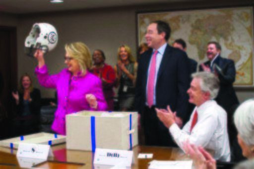 Hillary Clinton is given a helmet upon return to State
