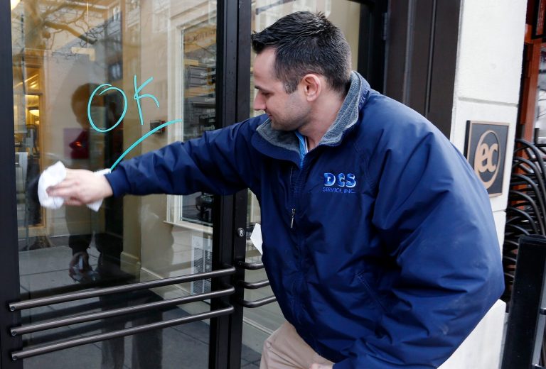 Antonio DaSilva, of Woburn, Mass., cleans a mark made on the entrance to a building on Boylston Street in Boston, Wednesday, April 24, 2013. Businesses opened and traffic was allowed to flow all the way down Boylston Street on Wednesday morning for the first time since two explosions at the Boston Marathon on April 15. (AP Photo/Michael Dwyer)