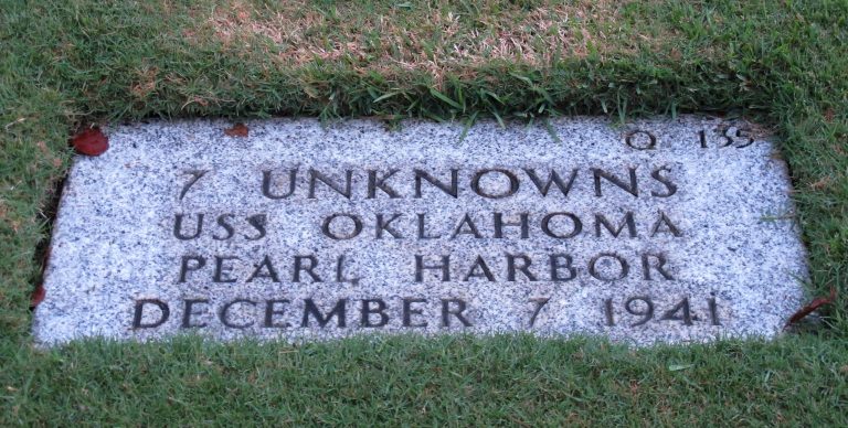   This Dec. 5, 2012 photo at the National Memorial Cemetery of the Pacific in Honolulu shows a gravestone identifying it as the resting place of 7 unknowns from the USS Oklahoma who died in Japanese bombing of Pearl Harbor. The Navy and National Park Service will honor Ray Emory, a Pearl Harbor survivor who pushed to put ship names on the gravestones and identify unknown remains, on Dec. 7 for his determination to have Pearl Harbor remembered, and remembered accurately. (AP Photo/Audrey McAvoy)  