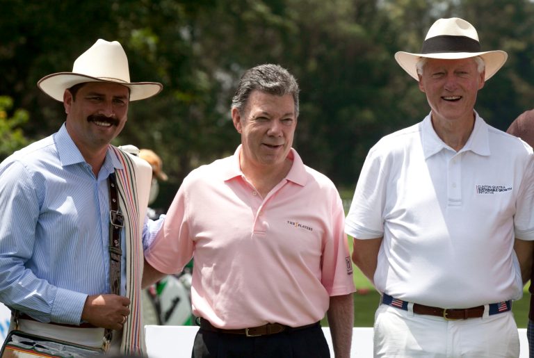 Colombia's President Juan Manuel Santos, center, and former President Bill Clinton, right, pose for a photo with Juan Valdez, left, the name of Colombia's top coffee brand before an exhibition golf game in Bogota, Colombia, Wednesday Feb. 15, 2012. Clinton is playing an exhibition tournament to raise funds for the Clinton Foundation, which is also the opening of the Pacific Rubiales Colombia Championship PGA tournament. (AP Photo/Fernando Vergara)