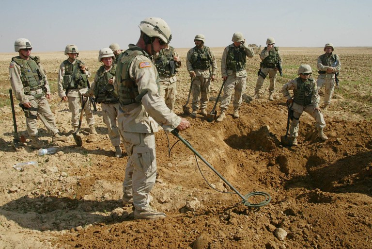 FILE  This Oct. 9, 2003 file photo shows soldiers from the U.S. Army's 720th Military Police Battalion watching as a mine sweeper look for weapons in a hole they dug during a raid on a farmland just outside Tikrit, Iraq. The Obama administration announced Friday that the US will no longer produce or acquire anti-personnel land mines and plans to join an international treaty banning their use.  (AP Photo/Karel Prinsloo, File)