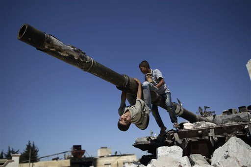 A  boy looks back while he and another boy play on a Syrian military tank, destroyed during fighting with the Rebels, in the Syrian town of Azaz, on the outskirts of Aleppo, Sunday, Sept. 2, 2012. (AP Photo/Muhammed Muheisen)