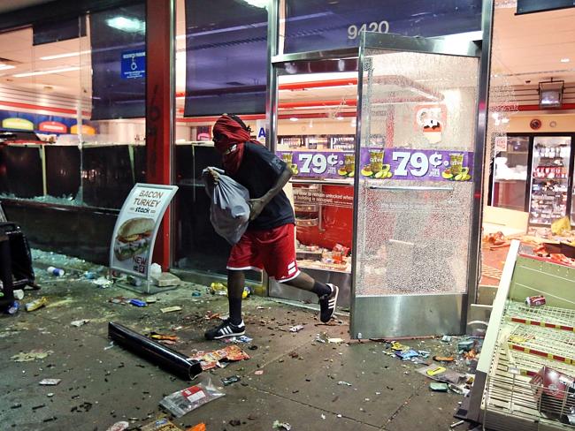 n the run ... a man flees a store in Ferguson, after riots broke out. Picture: AP /St. Louis Post-Dispatch, David Carson Source: AP