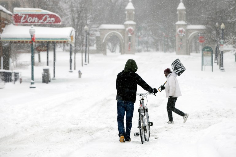   Heading toward Indiana University's Sample Gates, Yasukiko Aoliki, left, heads home after trekking downtown for a haircut only to find the business closed, Wednesday, Dec. 26, 2012 in Bloomington, Ind. (AP Photo/Bloomington Herald-Times, Jeremy Hogan)  