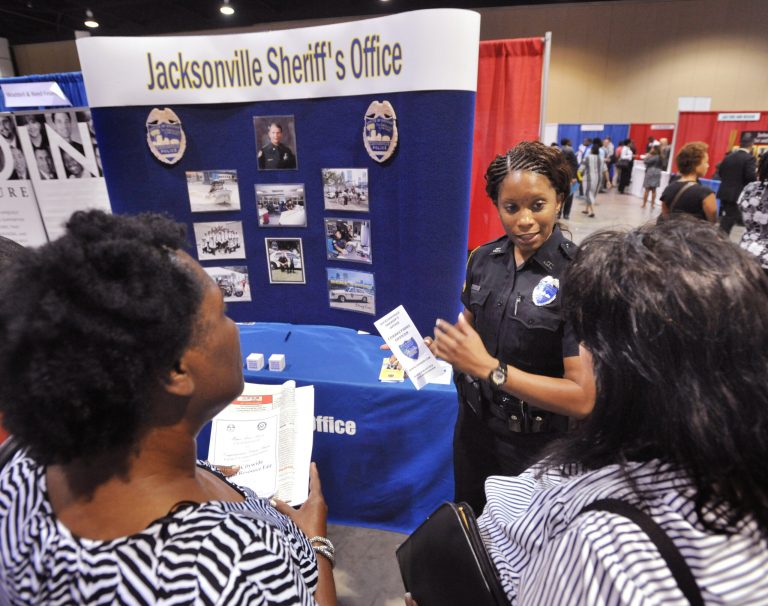 In this June 16, 2014 photo, Jacksonville police officer F. D. Williams, center, talks to job seekers during the City-Wide Job & Resource Fair at the Prime Osborn Convention Center in Jacksonville, Fla. The government reports on state unemployment rates for May on Friday, June 20, 2014. (AP Photo/The Florida Times-Union, Will Dickey)