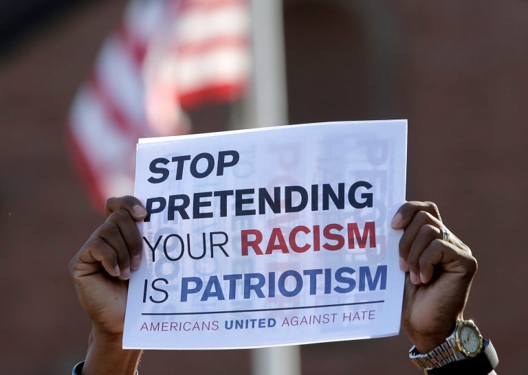 David Brown, of Plymouth, Mass., hands only, displays a placard during a protest Sunday, Aug. 13, 2017, in Plymouth The protest was held to denounce hatred and racism in response to a nationalist rally that spiraled into deadly violence in Charlottesville, Va., Saturday, Aug. 12, 2017. (AP Photo/Steven Senne)