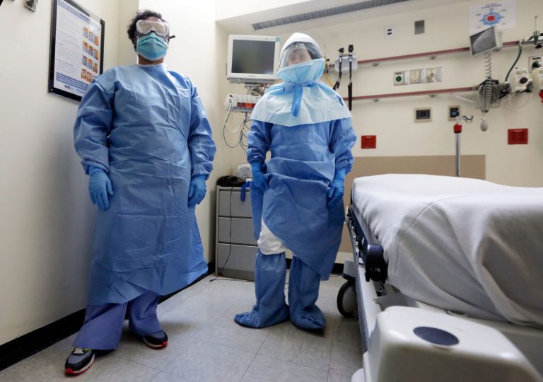 Bellevue Hospital nurse Belkys Fortune, left, and Teressa Celia, Associate Director of Infection Prevention and Control, pose in protective suits in an isolation room, in the Emergency Room of the hospital, during a demonstration of procedures for possible Ebola patients, Wednesday, Oct. 8, 2014. The U.S. government plans to begin taking the temperatures of travelers from West Africa arriving at five U.S. airports, including the New York area's JFK International and Newark Liberty International, as part of a stepped-up response to the Ebola epidemic. (AP Photo/Richard Drew)