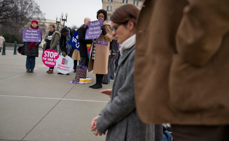Pro-choice demonstrators, left, watch as a group of anti-abortion demonstrators pray on the steps of the Supreme Court in Washington, Wednesday, Jan. 15, 2014. (AP Photo/ Evan Vucci)