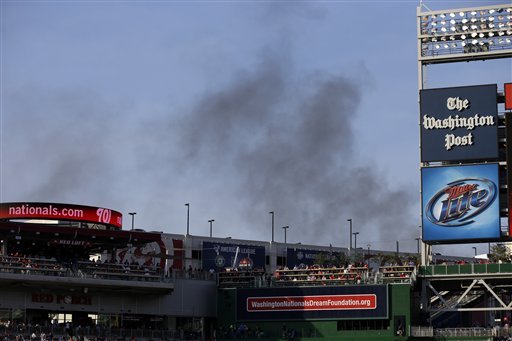 Smoke from a nearby hardware store fire rises behind Nationals Park before a baseball game between the Washington Nationals the New York Mets, Wednesday, June 5, 2013, in Washington. (AP Photo/Alex Brandon)