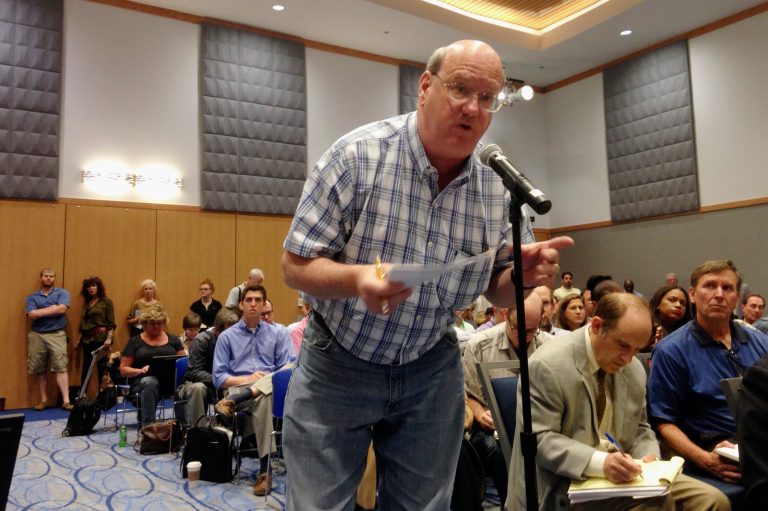 Brett Roeper asks a question Wednesday, Aug. 20, 2014, in Chicago during the last of three town hall meetings that gave patients, caregivers and aspiring business owners a chance to inquire about the application process for Illinois' medical marijuana program. Roeper wanted to know about whether dispensaries will be able to open medical marijuana packaging to let customers see and smell the product. A standing-room-only crowd of more than 500 attended the meeting. (AP Photo/Carla K. Johnson)