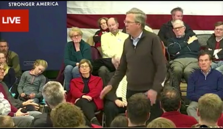 A woman seated directly behind Bush facing the press' cameras appeared unconscious until a man in yellow seated to her right elbowed her awake. (Screenshot)