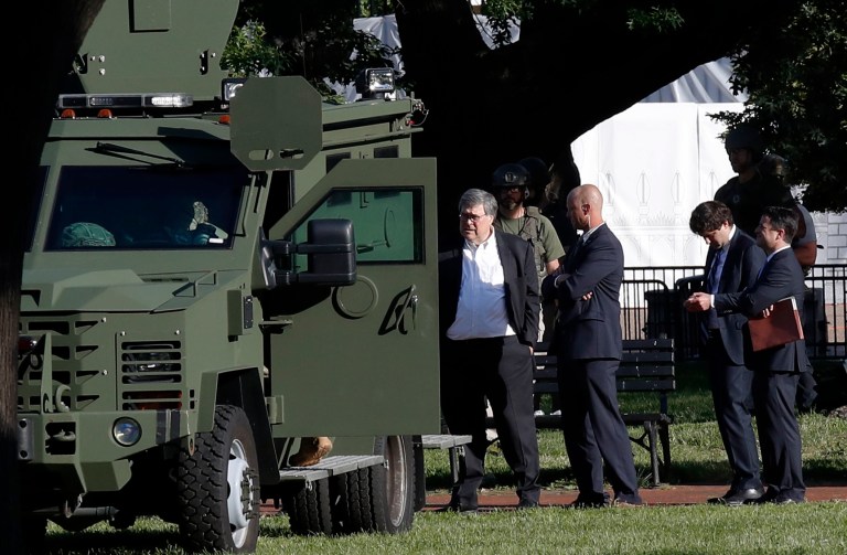 Attorney General William Barr, center, stands in Lafayette Park across from the White House as demonstrators gather to protest the death of George Floyd, Monday, June 1, 2020, in Washington. Floyd died after being restrained by Minneapolis police officers.