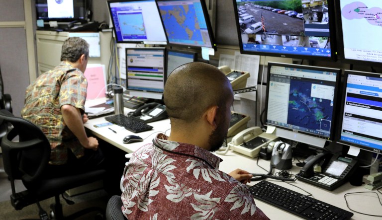 In this Dec. 1, 2017 file photo, Hawaii Emergency Management Agency officials work at the department's command center in Honolulu. The Hawaii government has conducted an internal review into the incident in which a day shift warning officer with the state's emergency management agency erroneously disseminated the message alerting more than 1 million people via cellphones, televisions, and radio stations of the supposed missile. (AP Photo/Caleb Jones, File)