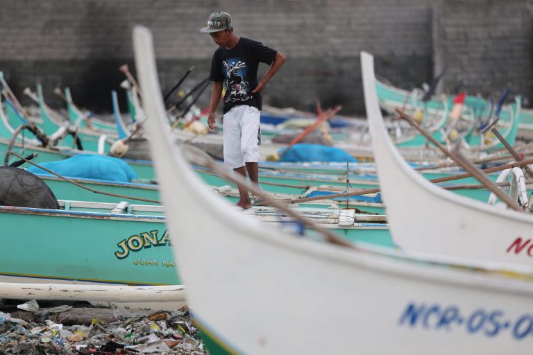 A Filipino walks small fishing boats docked beside a coastal village of Navotas, north of Manila, Philippines as they prepare for a coming storm on Monday, July 14, 2014. The Philippines is bracing for possible floods and landslides as Tropical Storm Rammasun, locally called 