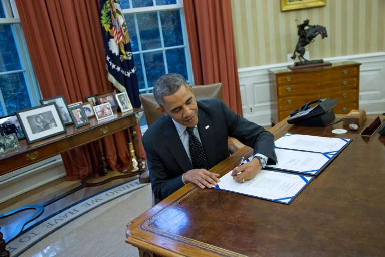 President Barack Obama signs H.R. 2747: the Streamlining Claims Processing for Federal Contractor Employees Act, Thursday, Nov. 21, 2013, in the Oval Office of the White House in Washington. (AP Photo/ Evan Vucci)