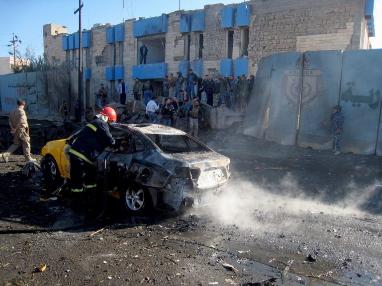 An Iraqi firefighter hoses down a burned car after a car bomb attack in Kirkuk, 180 miles (290 kilometers) north of Baghdad, Iraq, Tuesday, Jan. 7, 2014. Police said a suicide bomber rammed his explosives-laden truck into a police station, killing and wounding scores of people in the northern city, home to a mix of Arabs, Kurds and Turkomen, each of the ethnic groups has competing claims to the oil-rich area. (AP Photo/Emad Matti)