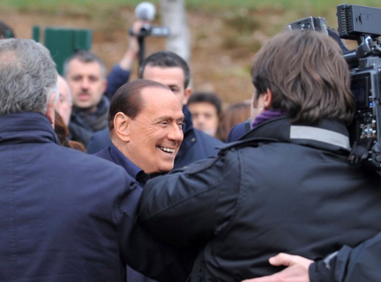   In this photo provided by AC Milan press office, billionaire media baron Silvio Berlusconi is surrounded by media as announces he is running for a fourth term as premier, during a visit to the AC Milan Milanello soccer training center, near Milan, Italy, Saturday, Dec. 8, 2012. 