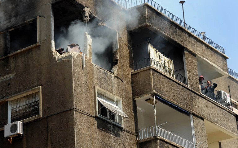 Syrian firefighters try to extinguish a fire after a missile hit a residential building in Damascus on Monday. (AP Photo/SANA)