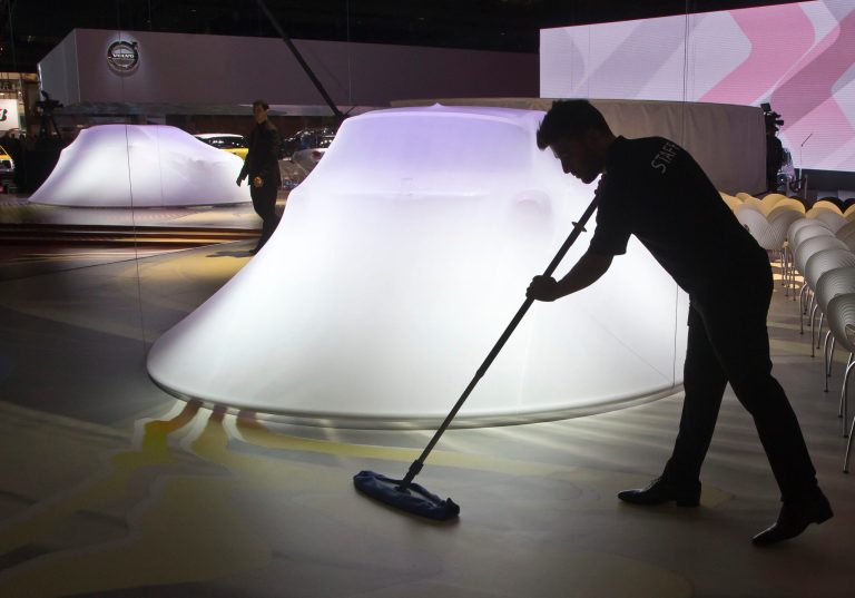 Worker cleans the floor next to a Fiat 500 X, in preparation for the press conference during the press day at the Motor Show in Paris, France, Thursday, Oct. 2, 2014. European carmakers are hoping to impress with new models at this week's Paris Motor Show and prove they have come out stronger from years of economic trouble and cost-cutting. (AP Photo/Michel Euler)