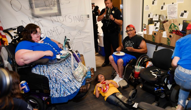 A Denver police officer, center back, asks protesters to vacate the offices of Republican Sen. Cory Gardner in downtown Denver, Colo., Thursday, June 29, 2017. Police later arrested the group of disabled protesters on Thursday evening who had spent three days camped out in Gardner's office, demanding that he pledge to oppose the GOP's health care plan. (Helen H. Richardson/The Denver Post via AP)