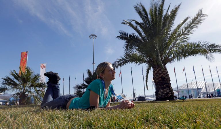 Oxsana Kharitonova lyes on the grass while posing for a photograph with friends on a sunny warm day at the 2014 Winter Olympics, Wednesday, Feb. 12, 2014, in Sochi, Russia. (AP Photo/David J. Phillip )