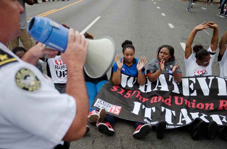 Protesters blocking Ponce de Leon Avenue outside a McDonald's restaurant are threatened with arrest during a protest demanding fast-food chains pay workers $15 an hour, Thursday, Sept. 4, 2014, in Atlanta. Calling for higher pay and the right to form a union without retaliation, fast-food chain workers in Atlanta protested Thursday as part of a wave of strikes and protests in 150 cities across the U.S. (AP Photo/David Goldman)